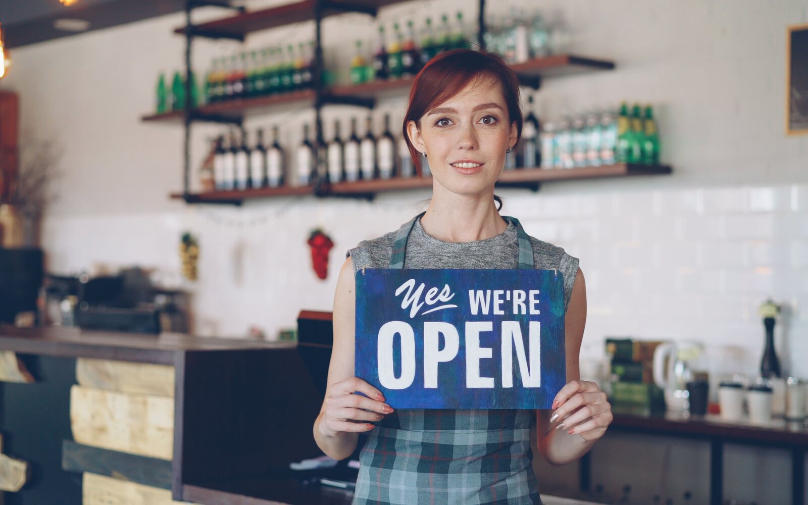 Small-business owner with an open sign, financed through a small-balance commercial loan